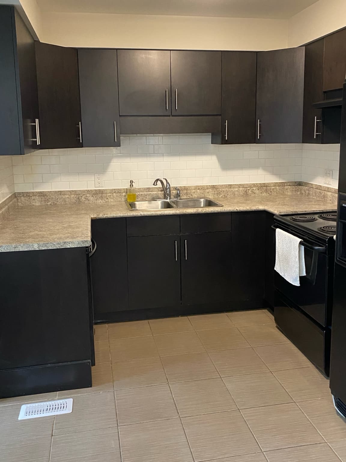 Kitchen with dark cabinets, tile backsplash, double sink and full-size range