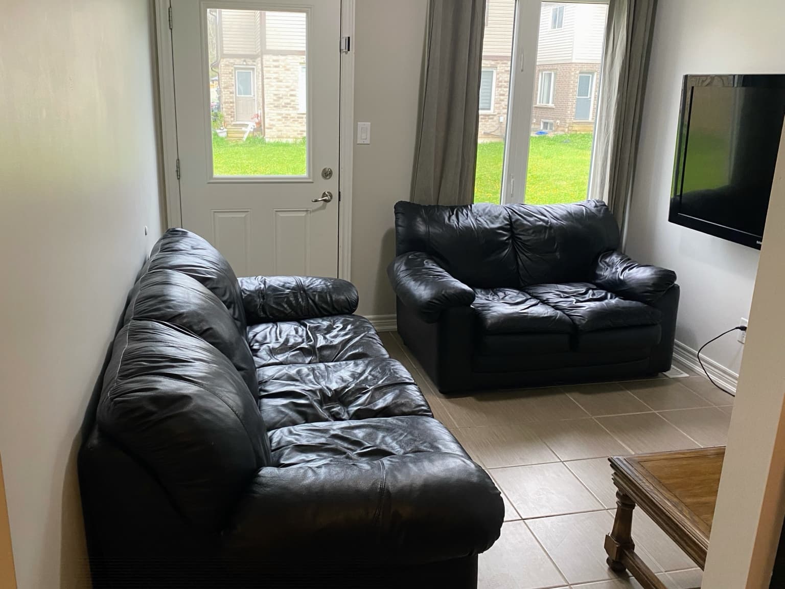 Shared living room with leather seating, TV and garden view