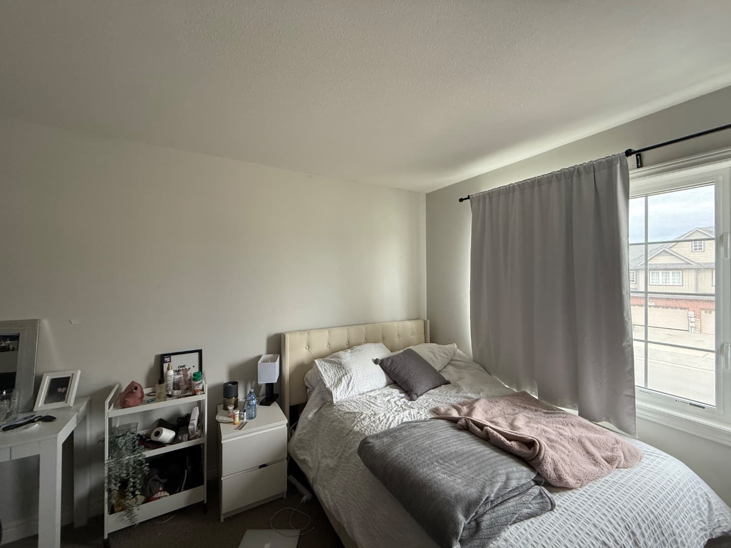 Bright upper-floor bedroom with tufted headboard and large window