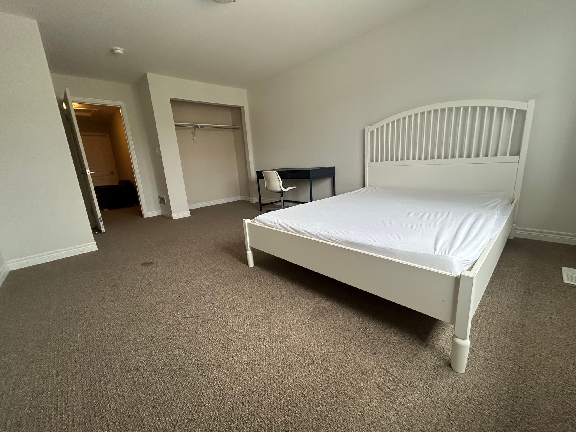 Spacious furnished master bedroom with a double bed, closet and desk